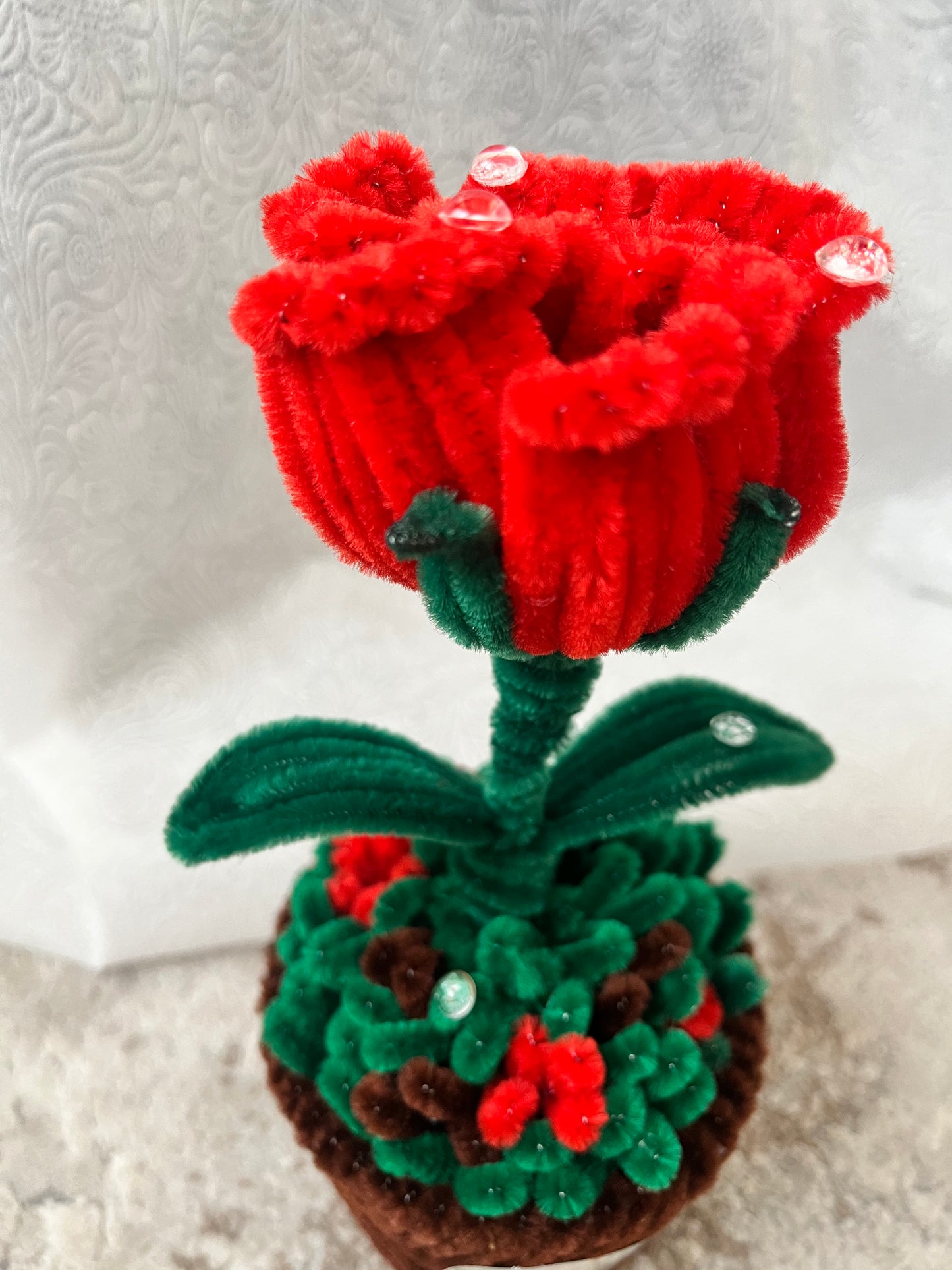 Detaljni prikaz plišanih latica crvene ruže sa kristalnim kapljicama