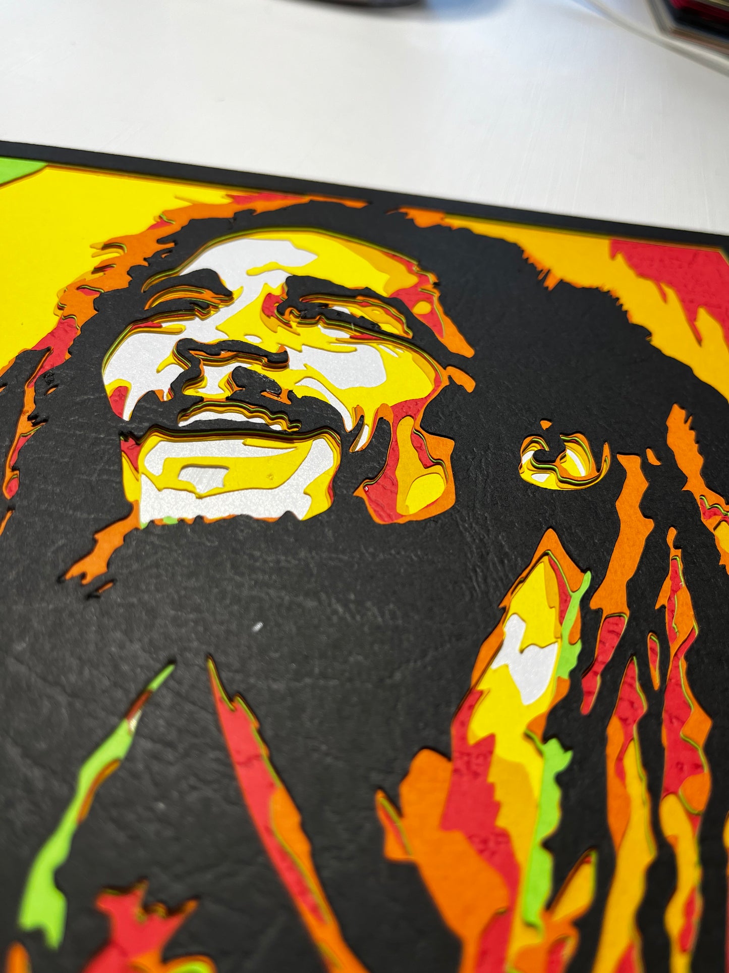 Detalj ručno rađene 3D papercut dekoracije Boba Marleyja – slojevi kartona u rasta bojama