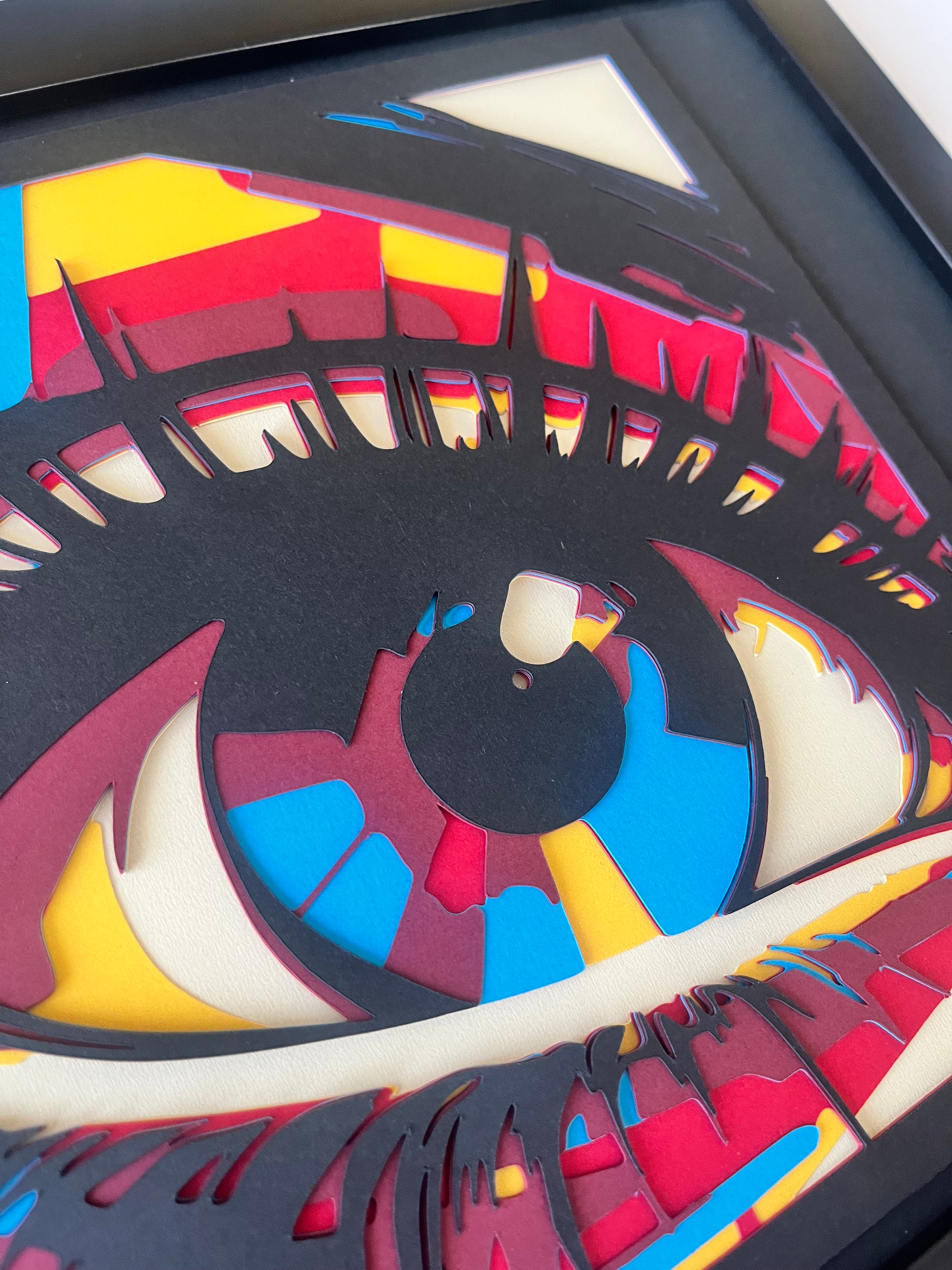 Detalj 3D shadow box slike oka sa slojevitom strukturom i živim bojama