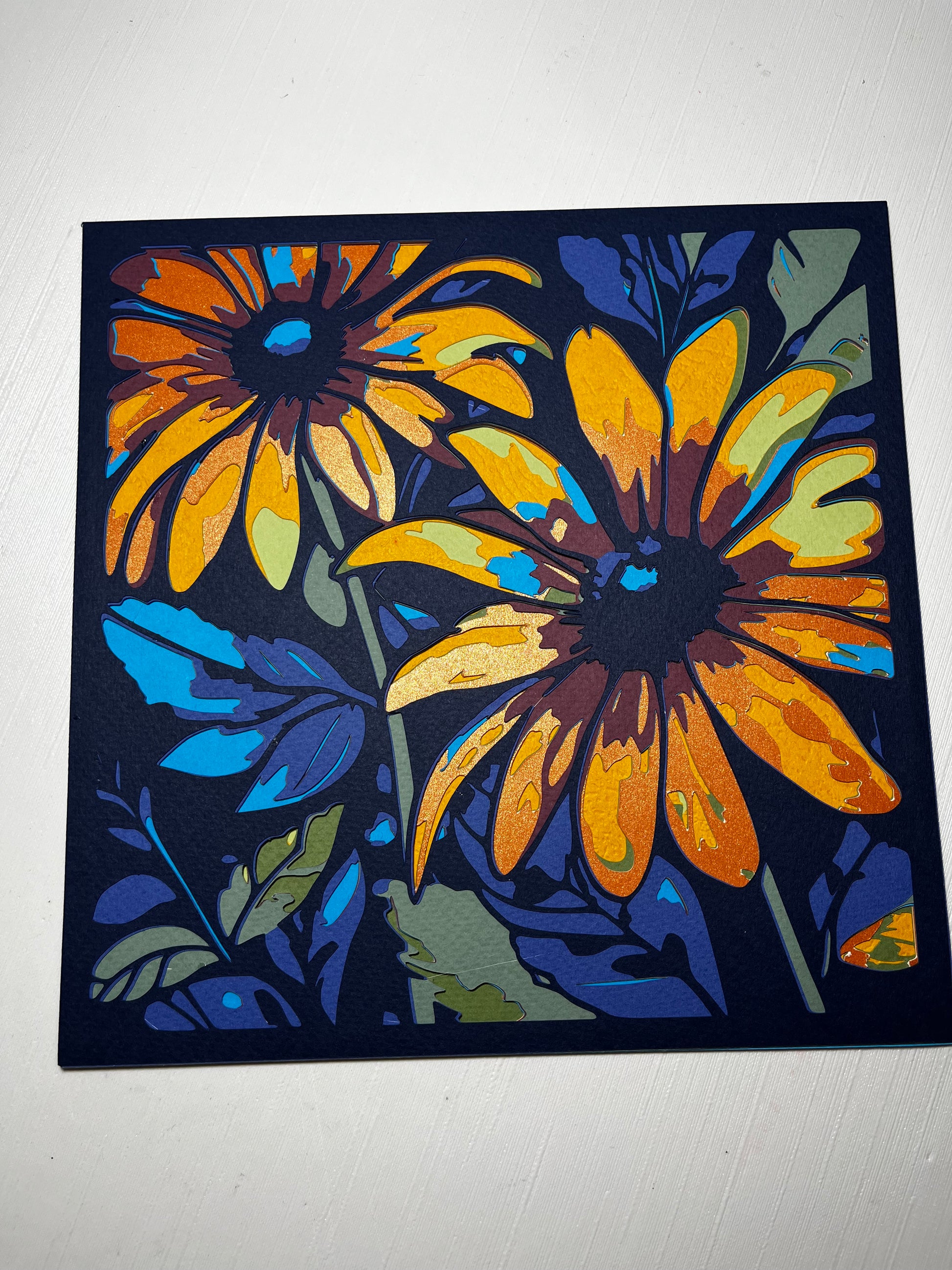 3D layered art dekoracija cveta – višeslojna papercut kompozicija zlatnih cvetova na tamno plavoj pozadini