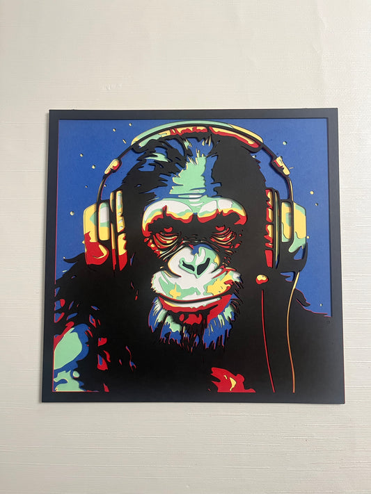 Višeslojna papercut zidna dekoracija u pop-art stilu – šimpanza sa slušalicama na plavoj pozadini, živopisne boje