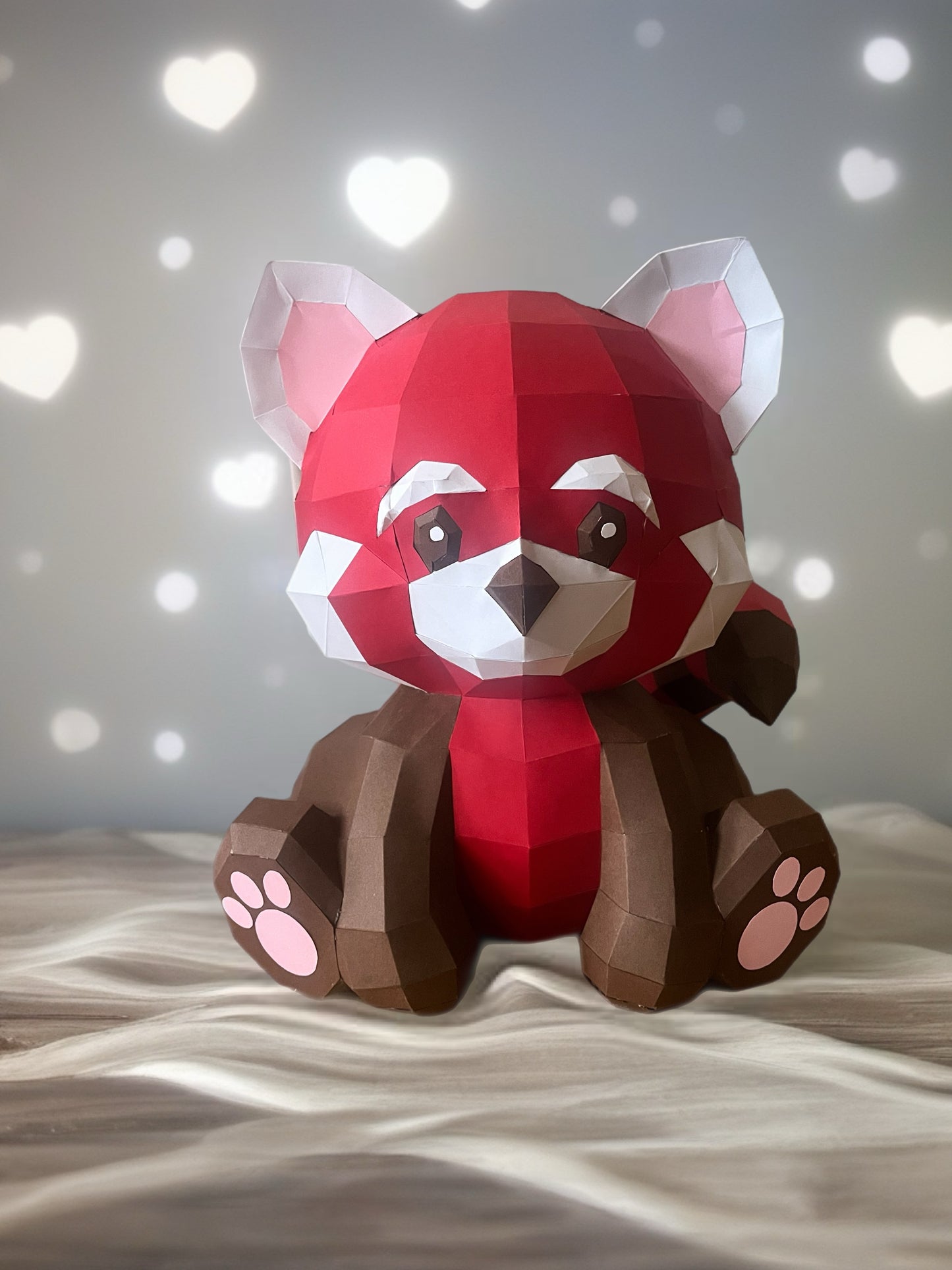 Low poly 3D papercraft skulptura crvene pande na beloj tkanini sa bokeh srcima u pozadini, romantični prikaz