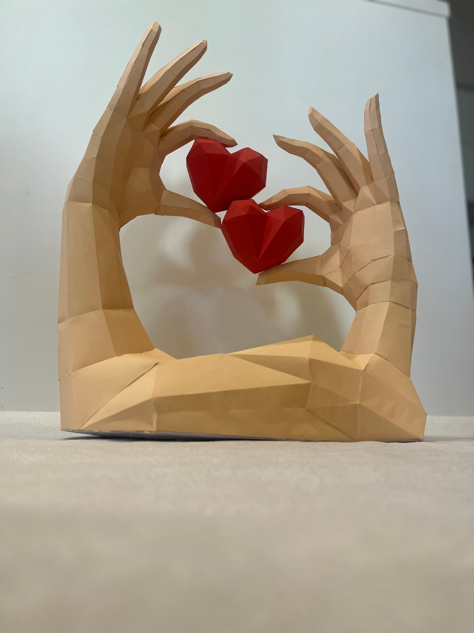 Low poly ruke sa srcima bočni pogled - prikazuje 3D geometrijske detalje i preciznost ručne izrade od kartona