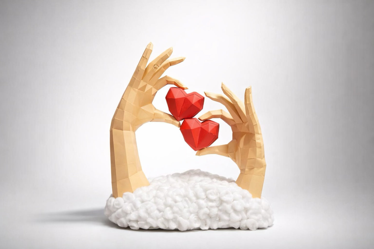 Low poly 3D skulptura dve ruke koje drže dva crvena srca, studio fotografija na beloj pozadini, papirna izrada