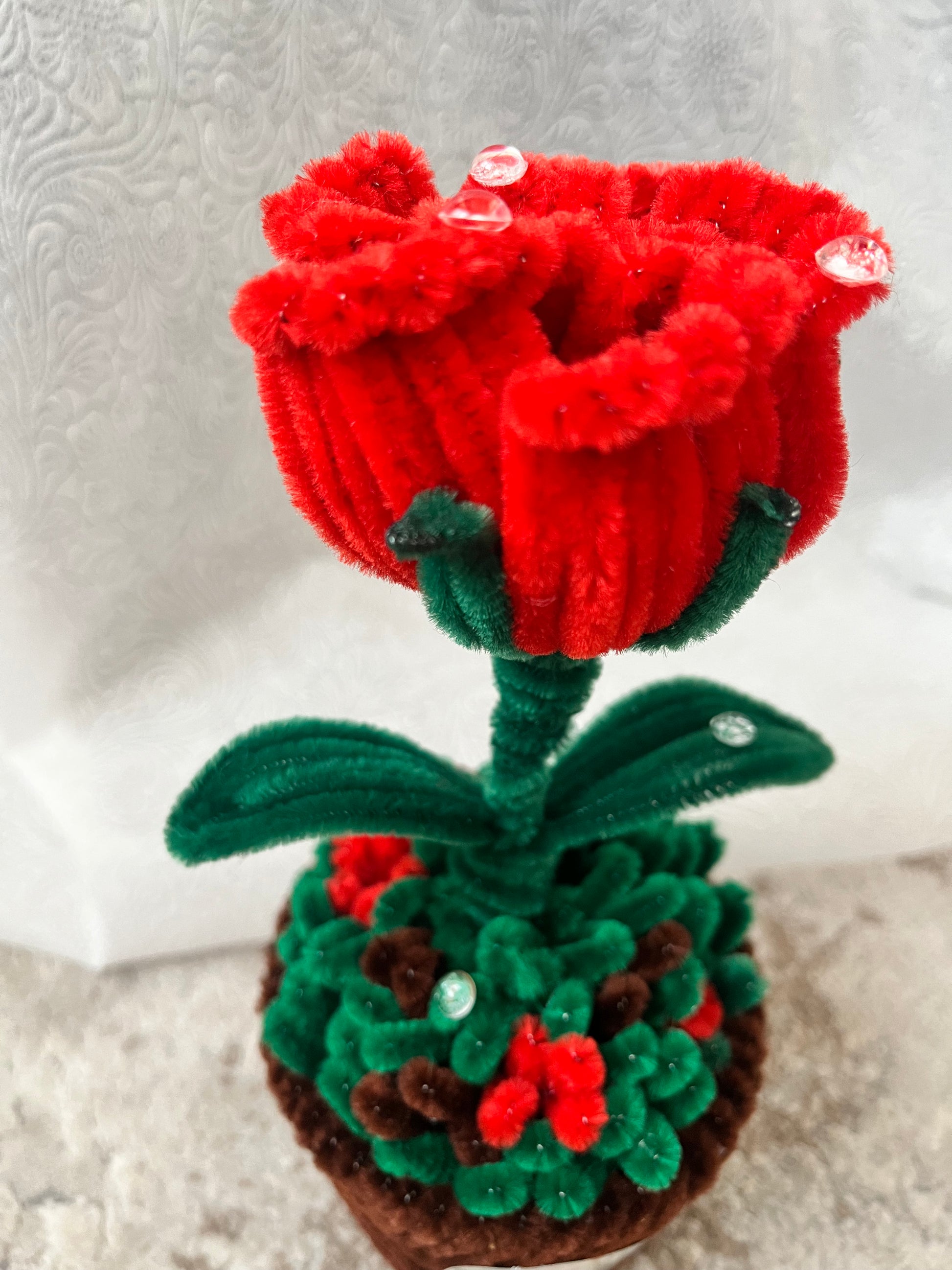 Detaljni prikaz plišanih latica crvene ruže sa kristalnim kapljicama