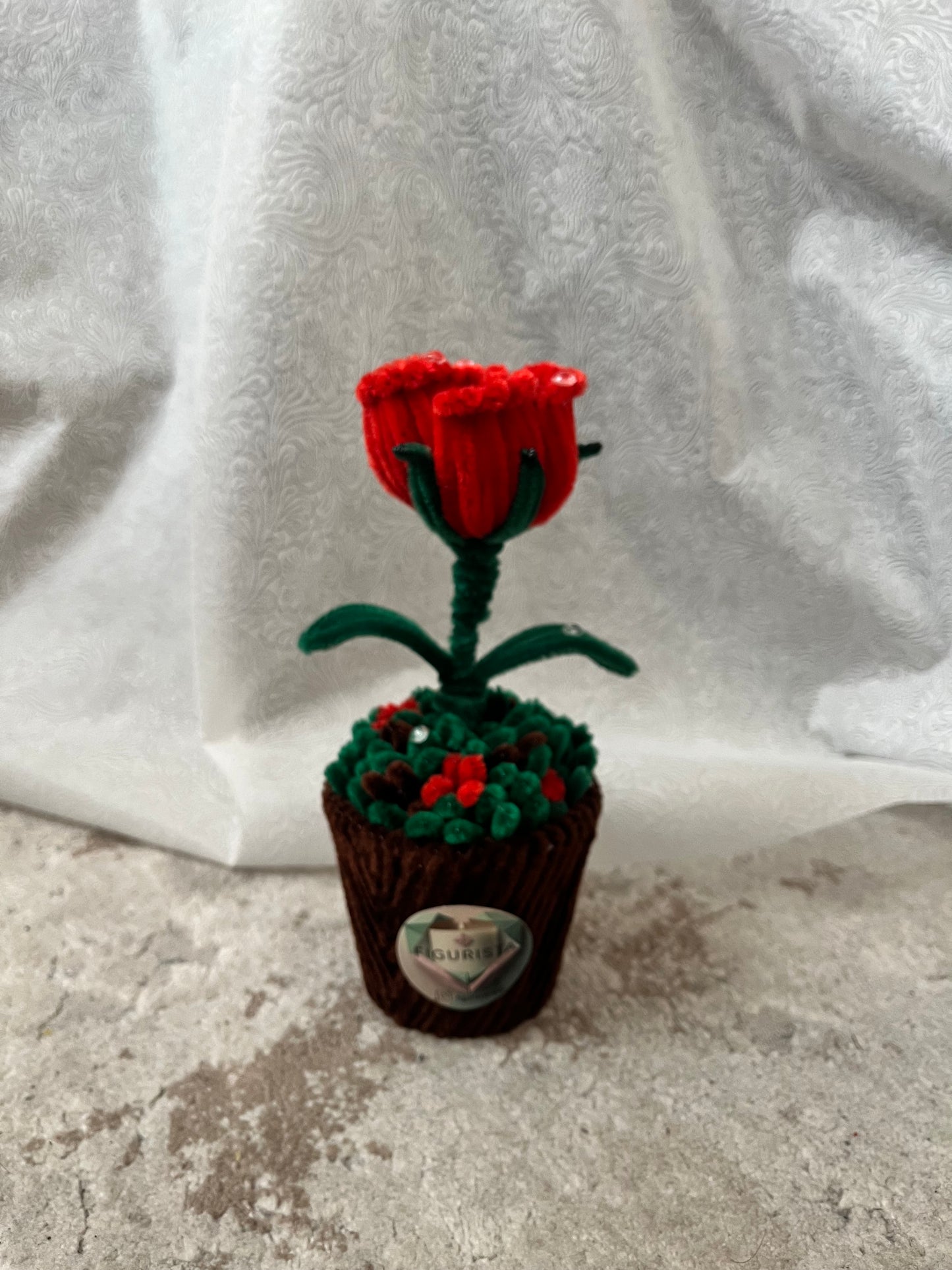 Plišano-žičani buket crvene ruže sa zelenim listovima u dekorativnoj saksiji, bočni pogled