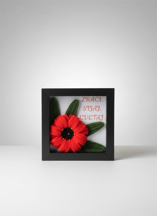 3D shadow box sa ručno rađenim crvenim makom od tkanine i porukom Zraci Sijaj Cvetaj u crvenoj kaligrafiji, crni okvir, bela pozadina