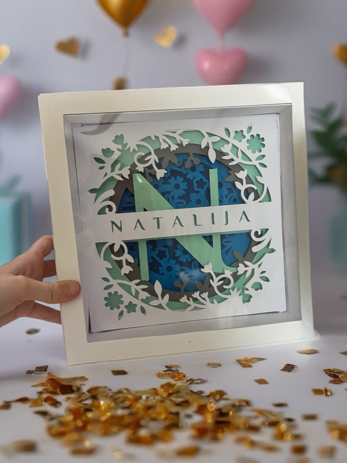 Shadow box sa inicijalom N i imenom Natalija držan u ruci - prikazuje 3D slojeve i dubinu ručno rađene dekoracije od kartona
