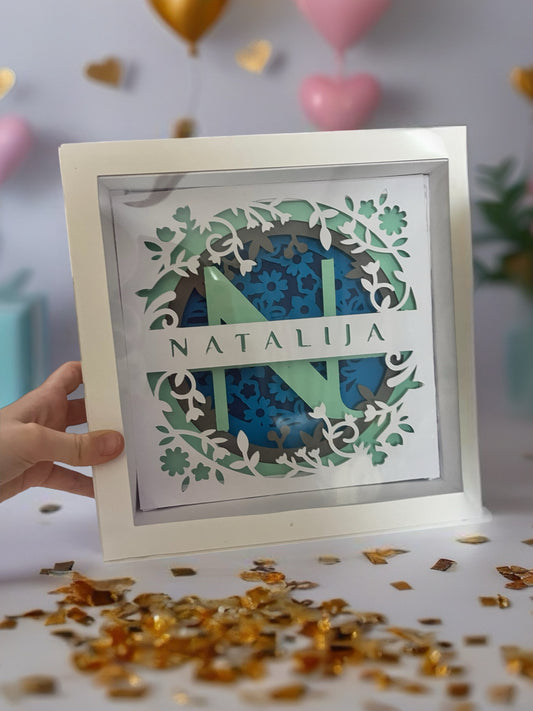Shadow box sa inicijalom N i imenom Natalija držan u ruci - prikazuje 3D slojeve i dubinu ručno rađene dekoracije od kartona
