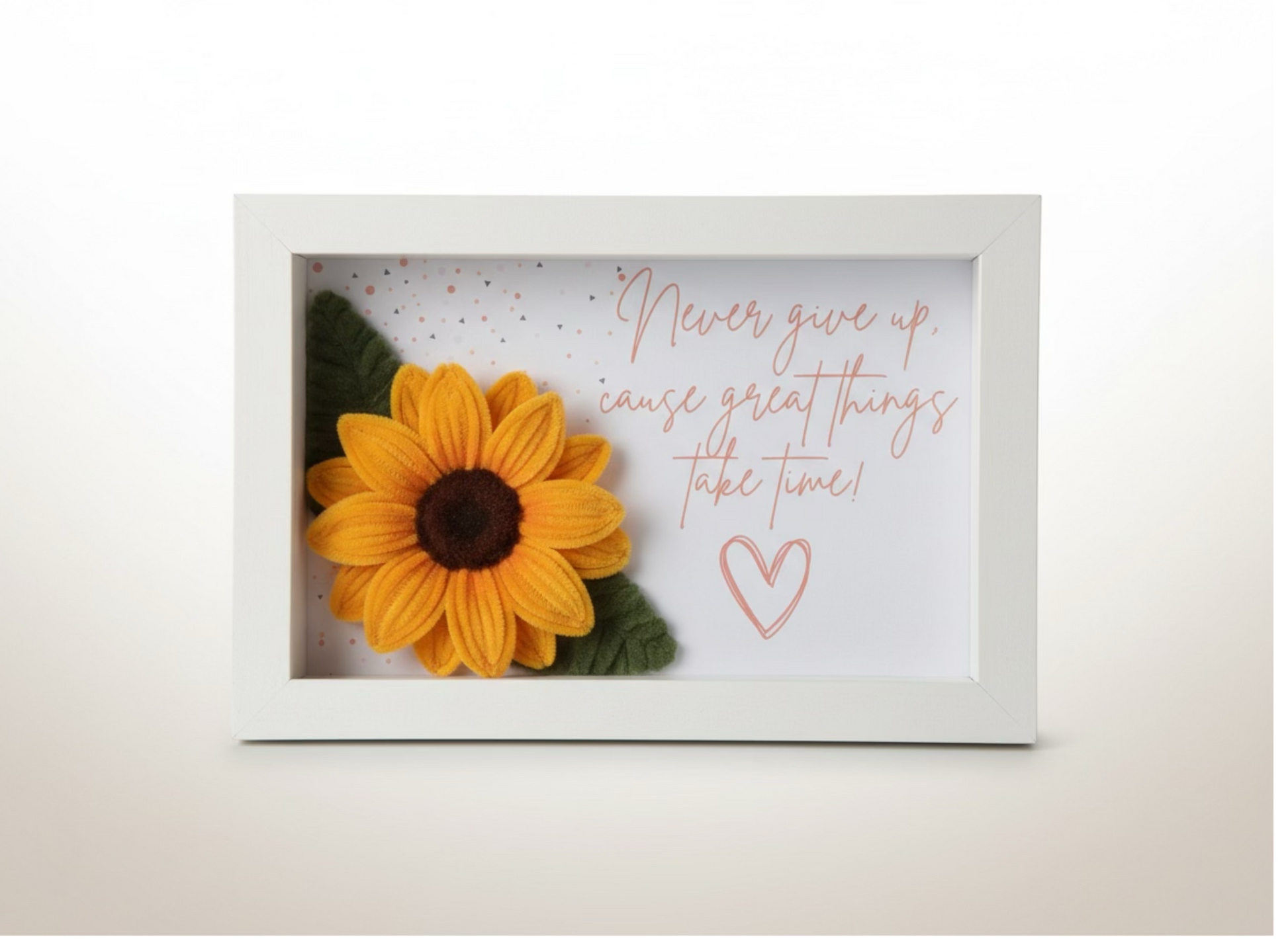 3D shadow box sa ručno rađenim suncokretom od pliša i motivacionom porukom Never give up u roze kaligrafiji, beli okvir
